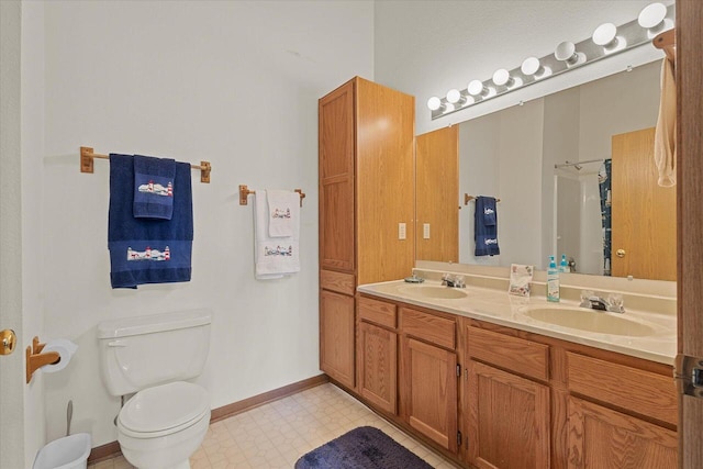 bathroom with a sink, baseboards, toilet, and double vanity