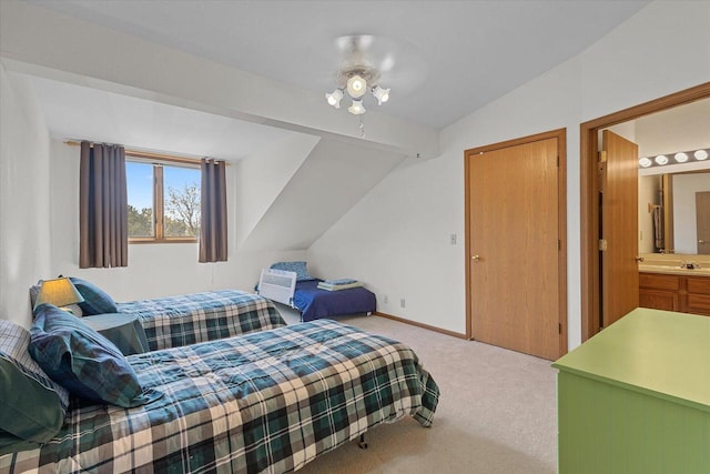 bedroom with baseboards, light colored carpet, a sink, ensuite bath, and vaulted ceiling