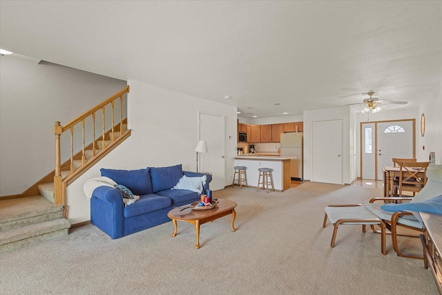 living room with ceiling fan, light carpet, and stairs