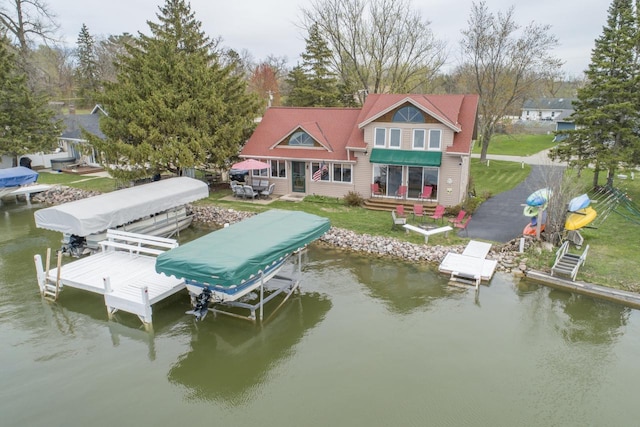view of dock featuring boat lift, a water view, and a yard
