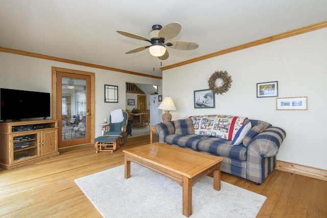 living room featuring light wood-type flooring, a ceiling fan, baseboards, and crown molding