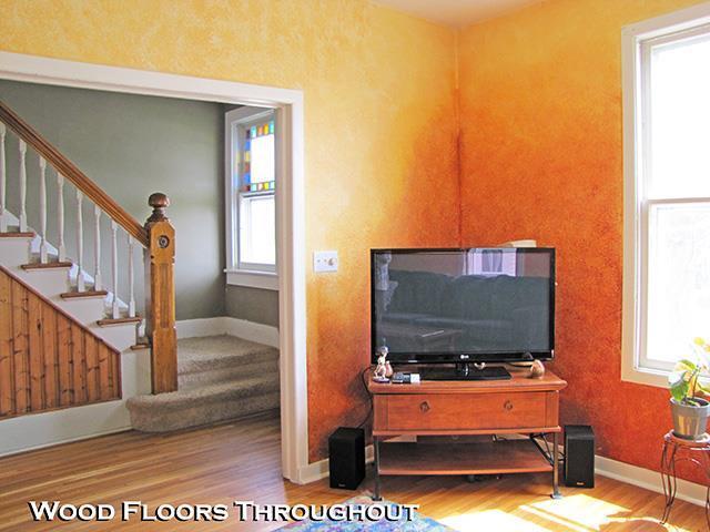 living room with baseboards, wood finished floors, and stairway