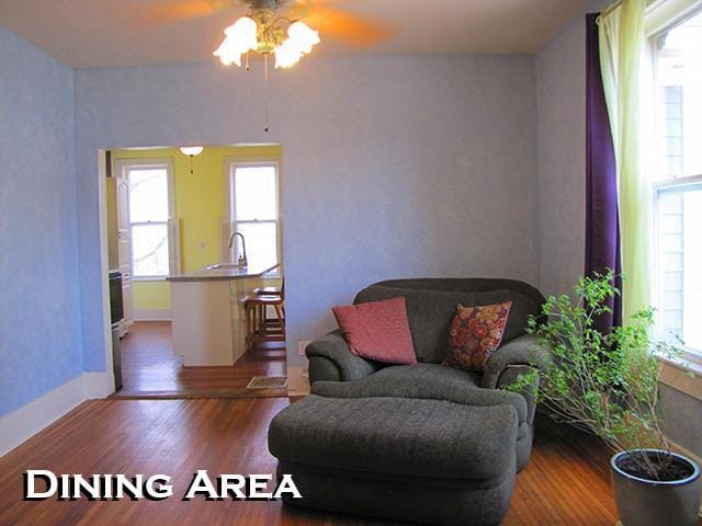 living area with baseboards, ceiling fan, and wood finished floors