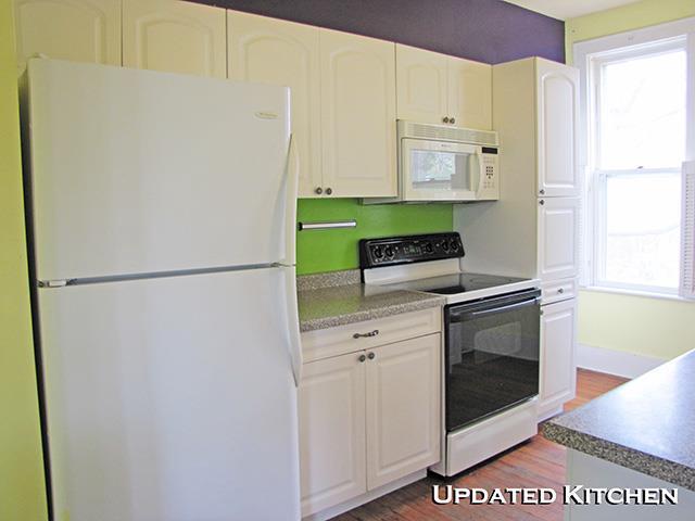 kitchen featuring white appliances, white cabinets, a healthy amount of sunlight, and wood finished floors