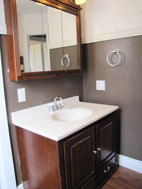 bathroom featuring baseboards, wood finished floors, and vanity