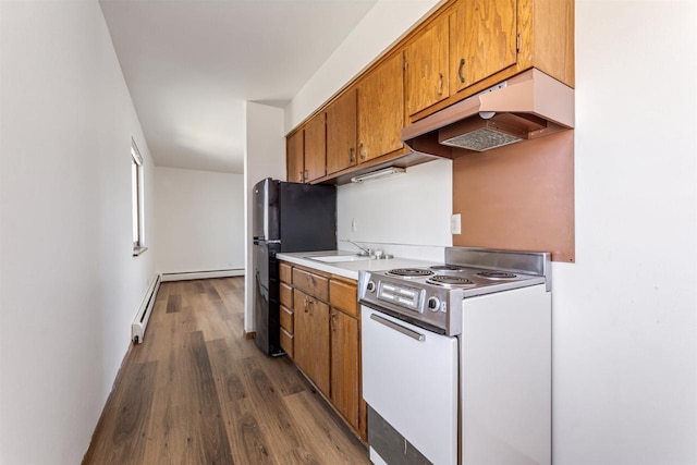 kitchen with dark wood-style flooring, white electric range, brown cabinets, a baseboard heating unit, and under cabinet range hood