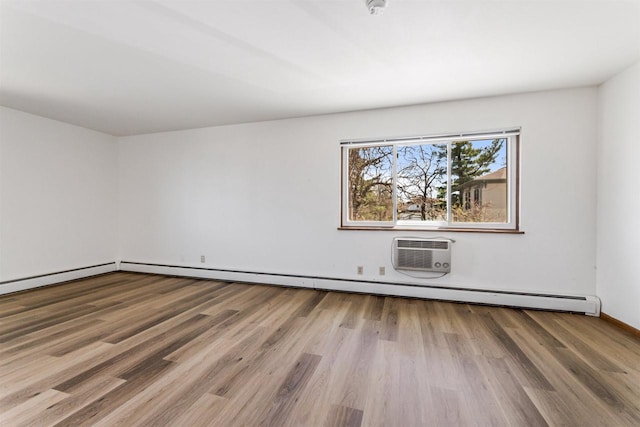 spare room featuring baseboards, a wall mounted AC, a baseboard heating unit, and wood finished floors