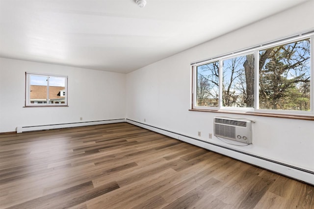 spare room with a baseboard radiator, a wall unit AC, and wood finished floors
