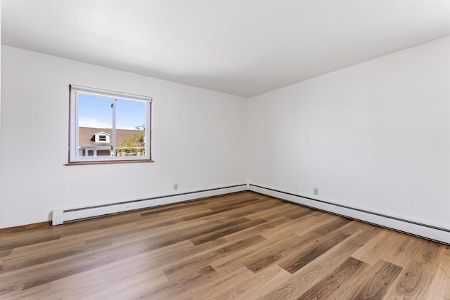 unfurnished room with a baseboard radiator and wood finished floors