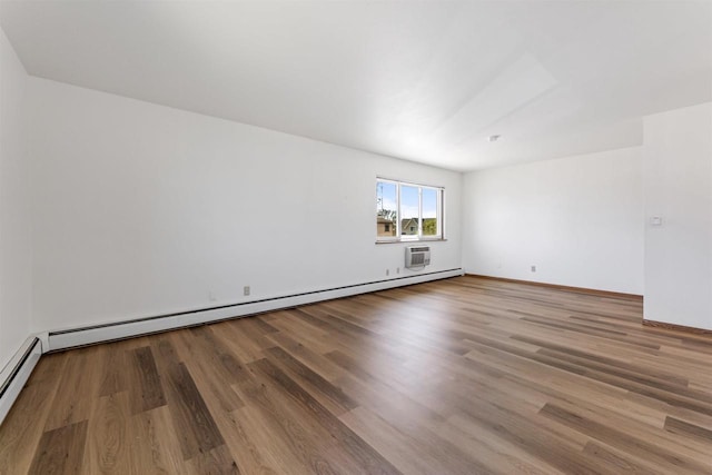 spare room with baseboards, a baseboard radiator, and wood finished floors
