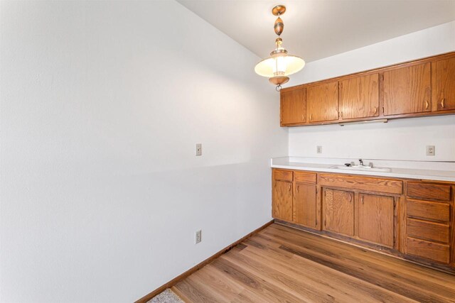 kitchen featuring a sink, light wood finished floors, brown cabinets, and light countertops