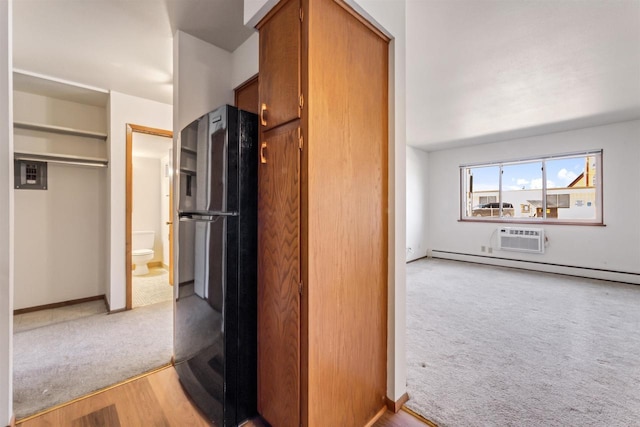 kitchen featuring brown cabinets, light colored carpet, freestanding refrigerator, a baseboard heating unit, and a wall mounted AC