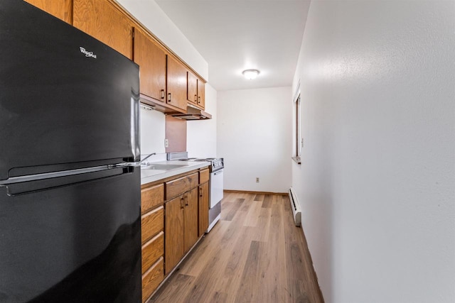kitchen with brown cabinetry, freestanding refrigerator, light wood-style floors, a baseboard radiator, and white electric stove
