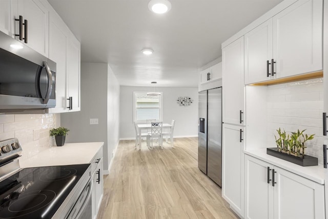 kitchen with light wood-type flooring, light countertops, white cabinetry, appliances with stainless steel finishes, and backsplash