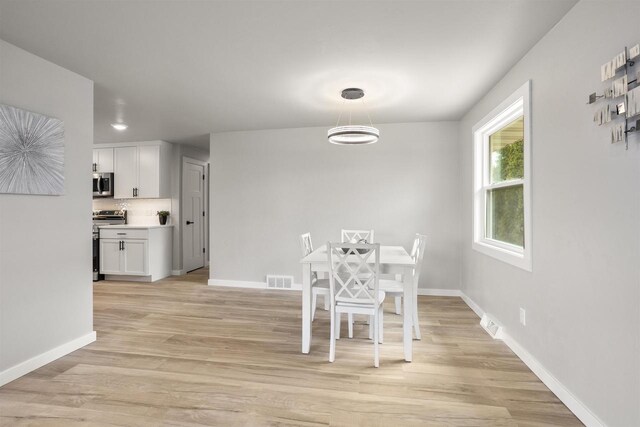 dining area featuring baseboards and light wood finished floors