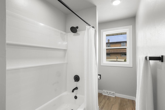 bathroom featuring visible vents, shower / tub combo with curtain, baseboards, and wood finished floors