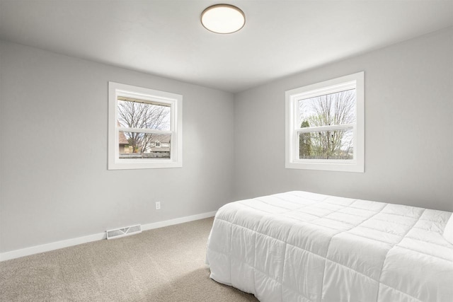 carpeted bedroom featuring visible vents, baseboards, and multiple windows