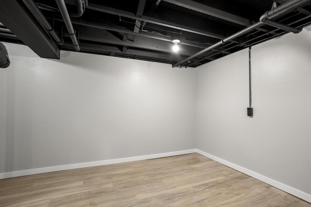 finished below grade area with baseboards and wood finished floors
