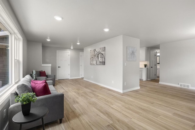 living room with recessed lighting, baseboards, visible vents, and light wood finished floors