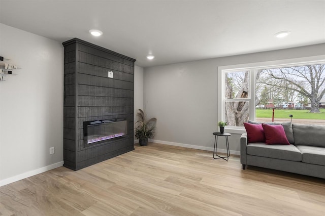 sitting room with baseboards, recessed lighting, light wood finished floors, and a large fireplace