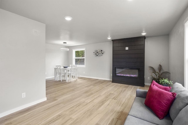 living area with recessed lighting, a large fireplace, baseboards, and light wood-type flooring