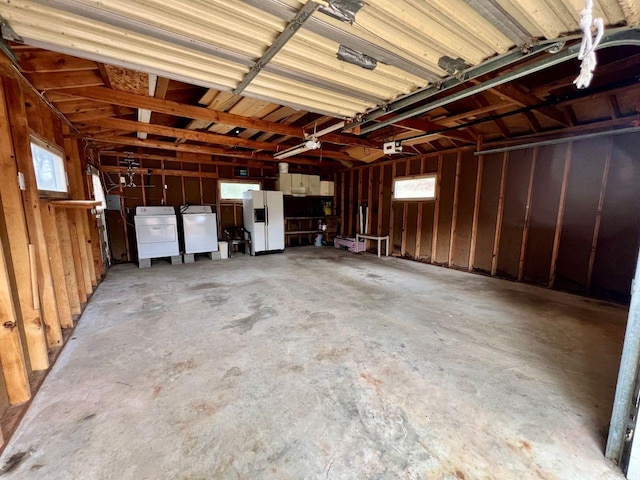 garage with separate washer and dryer, a garage door opener, and white refrigerator with ice dispenser