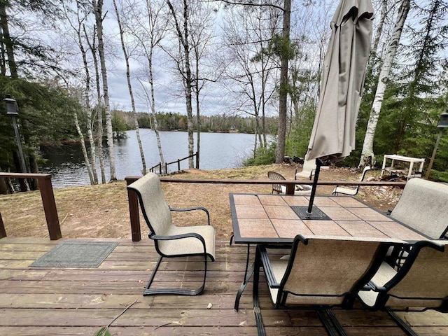 wooden deck with a water view and outdoor dining space