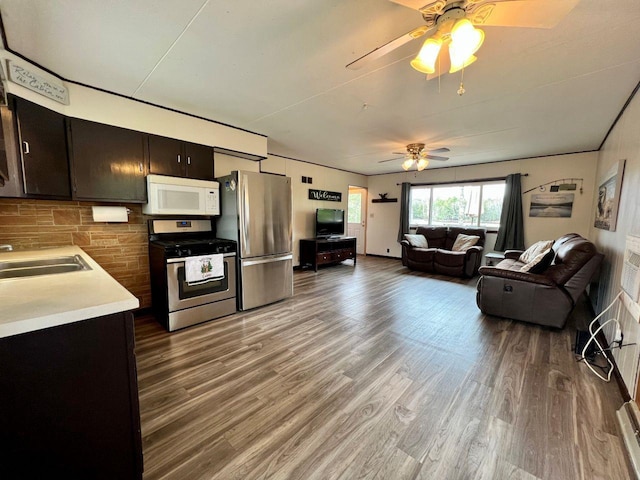 kitchen with a ceiling fan, appliances with stainless steel finishes, wood finished floors, a sink, and light countertops