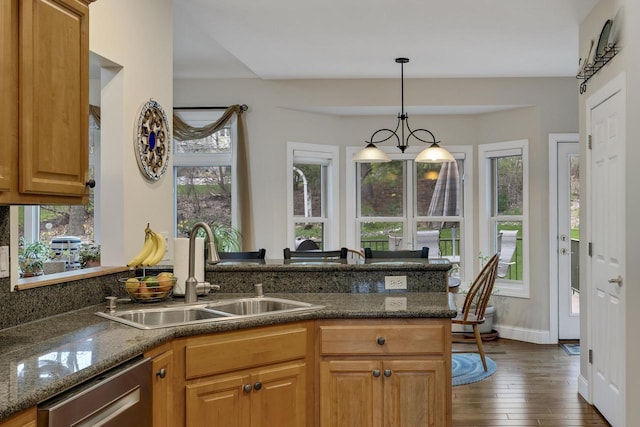 kitchen with a sink, a healthy amount of sunlight, dark stone countertops, and dishwasher