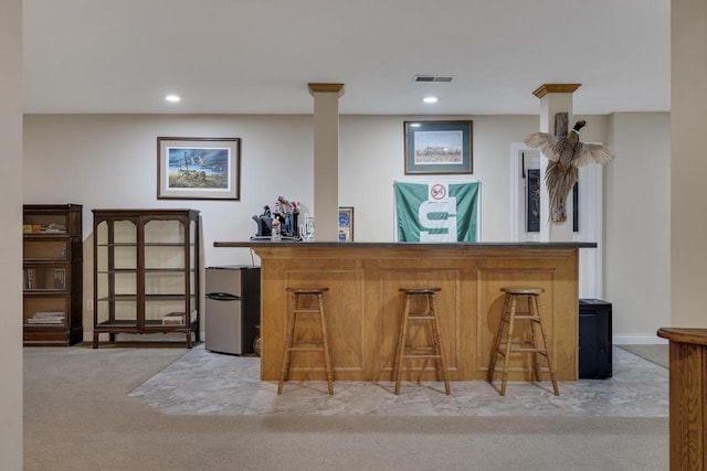 bar featuring freestanding refrigerator, light colored carpet, visible vents, and a dry bar