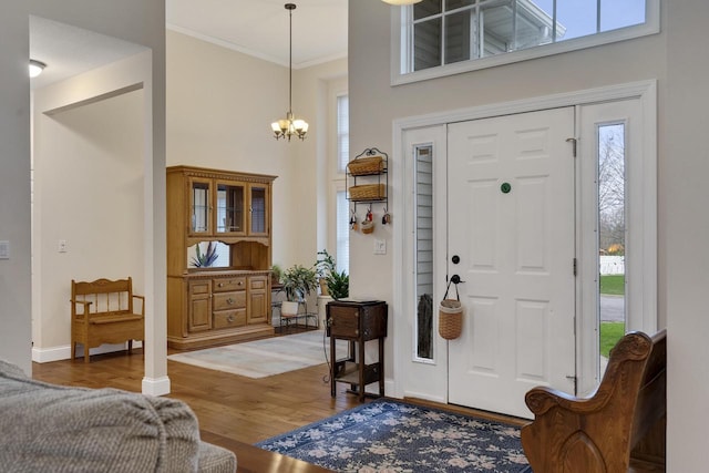 entryway featuring a high ceiling, an inviting chandelier, a healthy amount of sunlight, and light wood-type flooring