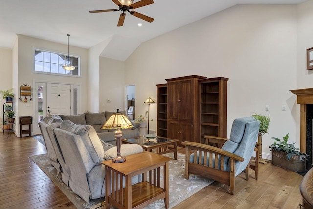 living area with light wood-style floors, ceiling fan, and high vaulted ceiling