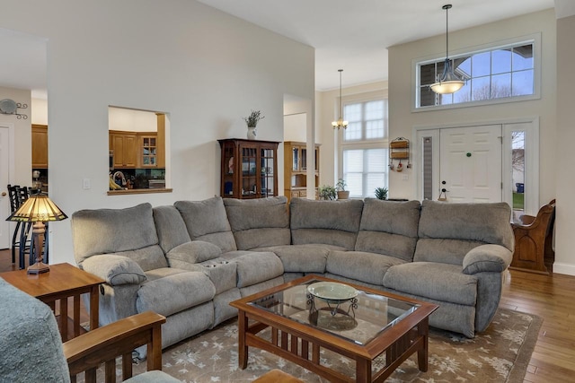 living room with a high ceiling, a chandelier, and wood finished floors