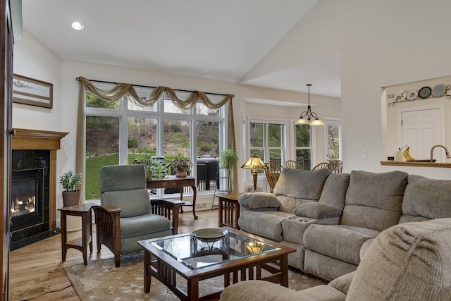 living area featuring recessed lighting, vaulted ceiling, light wood-type flooring, and a premium fireplace