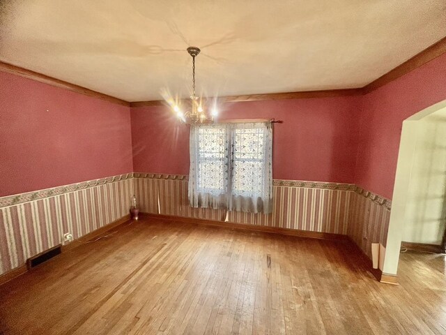 227 1st St, Baraboo, WI 53913 - unfurnished dining area featuring arched walkways, a chandelier, and hardwood / wood-style floors