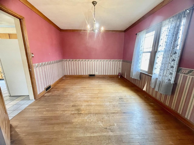227 1st St, Baraboo, WI 53913 - unfurnished dining area featuring ornamental molding, wood-type flooring, a notable chandelier, and visible vents