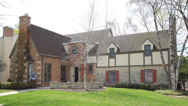 exterior space with roof with shingles, brick siding, stone siding, stucco siding, and a front yard