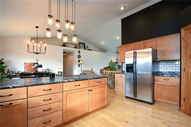 4410 Echo Valley Dr, Eau Claire, WI 54701 - kitchen with decorative backsplash, light wood-style floors, stainless steel fridge, a notable chandelier, and vaulted ceiling