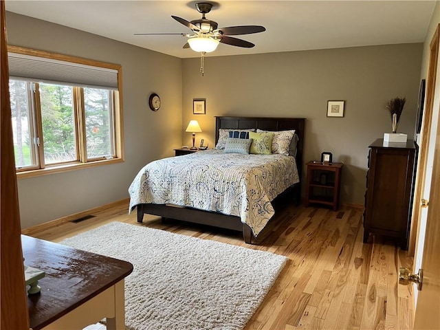 bedroom featuring visible vents, light wood-style flooring, ceiling fan, and baseboards