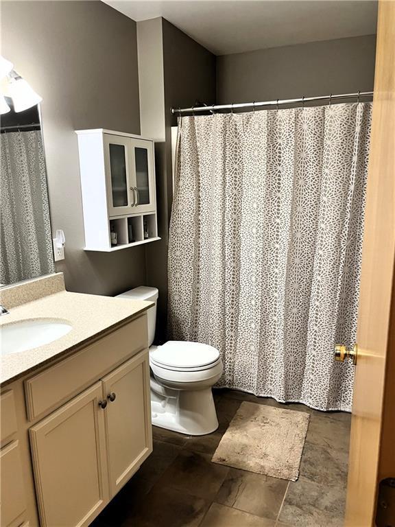 bathroom with vanity, stone finish floor, and toilet