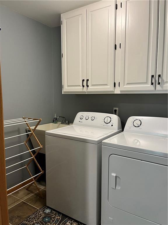 clothes washing area with dark tile patterned flooring, cabinet space, and independent washer and dryer