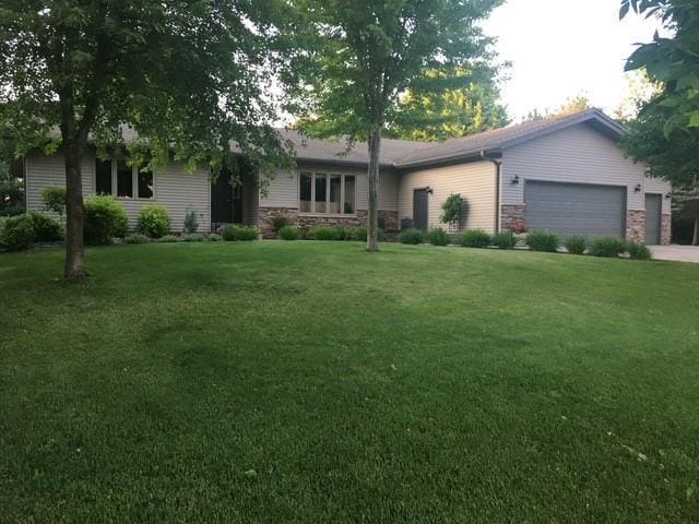 single story home with a garage, driveway, a front lawn, and stone siding