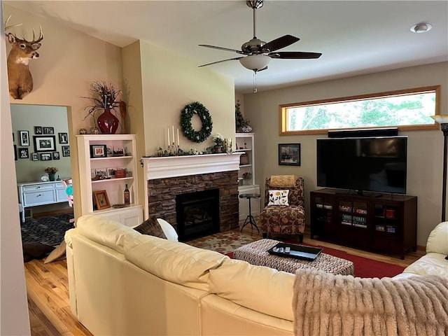 living area with a ceiling fan, wood finished floors, and a fireplace