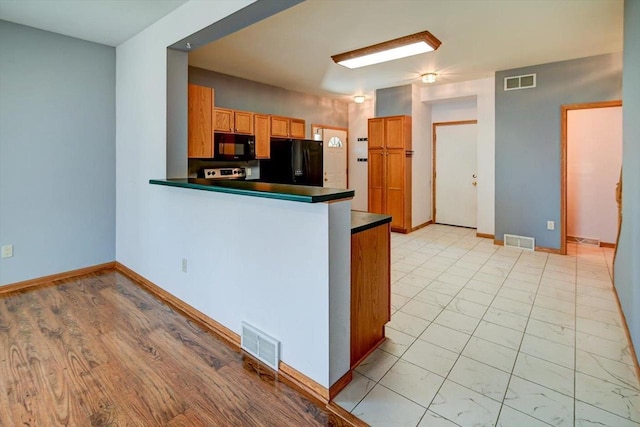 555 Kelvington Dr Unit 4, Sun Prairie, WI 53590 - kitchen featuring black appliances, dark countertops, a peninsula, baseboards, and brown cabinetry