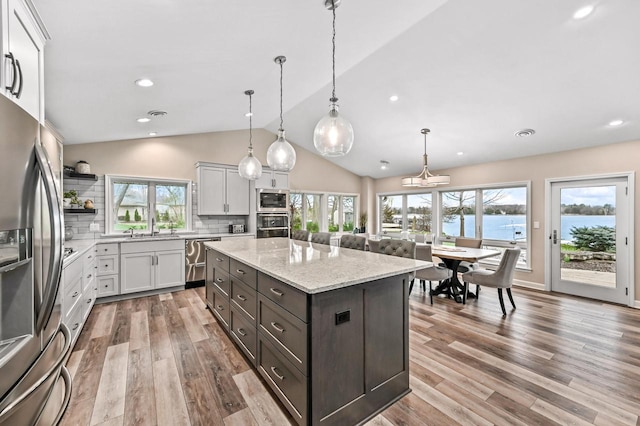 kitchen with a kitchen island, appliances with stainless steel finishes, tasteful backsplash, open shelves, and vaulted ceiling