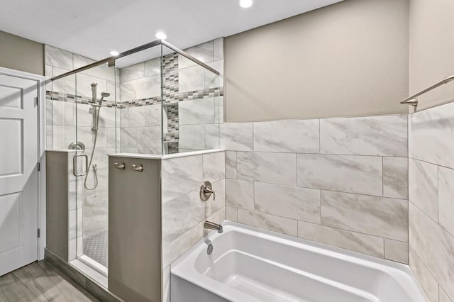 bathroom with recessed lighting, an enclosed shower, and a tub