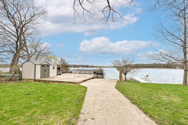 view of yard with a storage unit, an outbuilding, a water view, and a dock