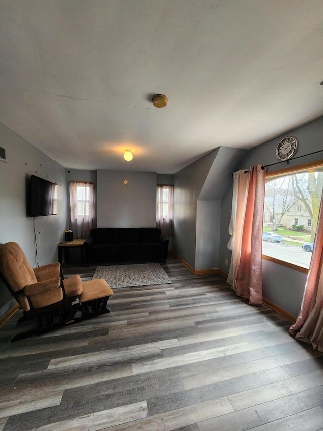 living room with baseboards, visible vents, and wood finished floors