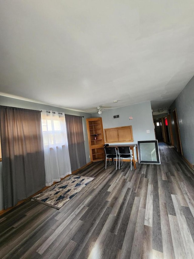 living area with baseboards, ceiling fan, wood finished floors, and visible vents