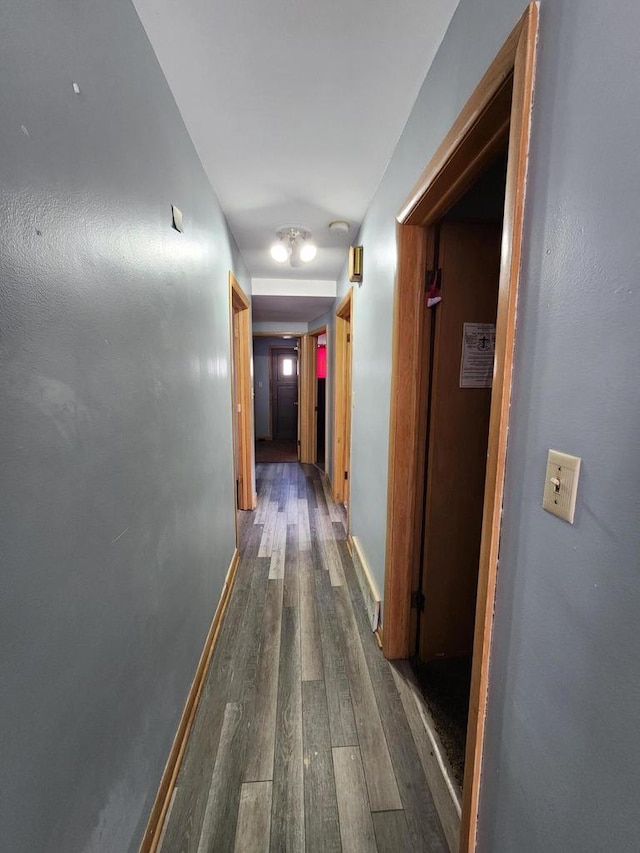 hall featuring baseboards and dark wood finished floors